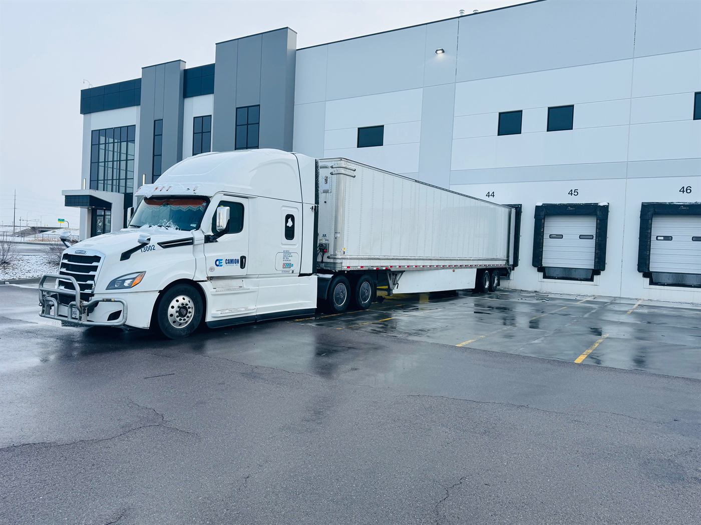 White Camion Express tractor and 53-foot trailer backed into a warehouse dock